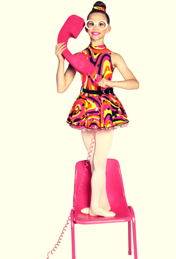 Girl in a retro dance costume standing on a bright pink chair holding onto an oversized pink phone