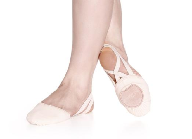 Person wearing a pair of pink canvas half ballet shoes