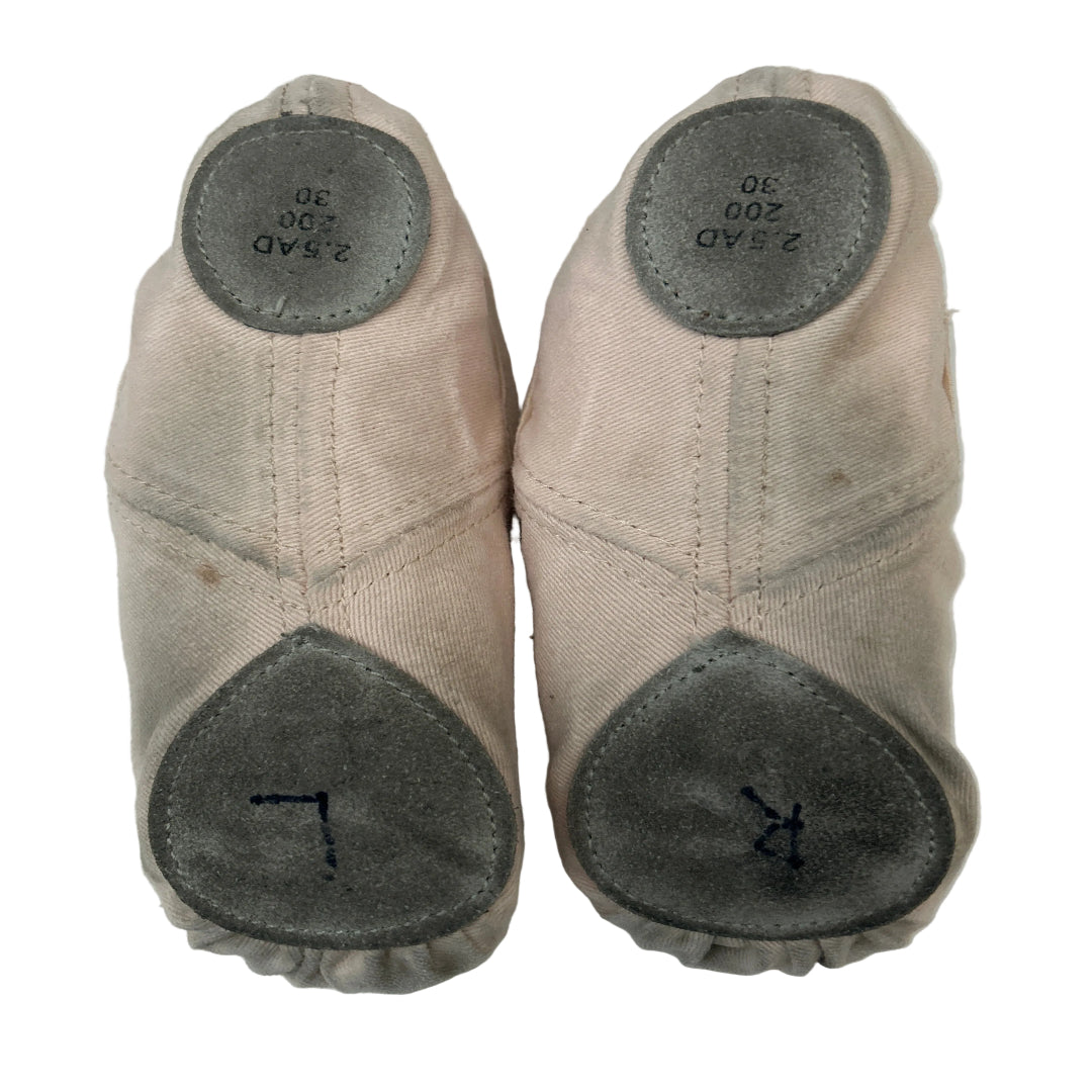 Bottom view of a pair of second hand canvas ballet shoes with criss cross elastic straps