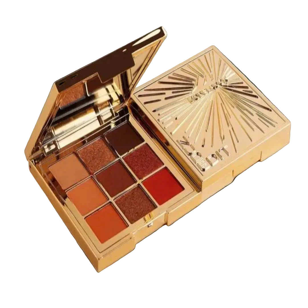 Makeup palette with brown and red shades in a gold case on a white background