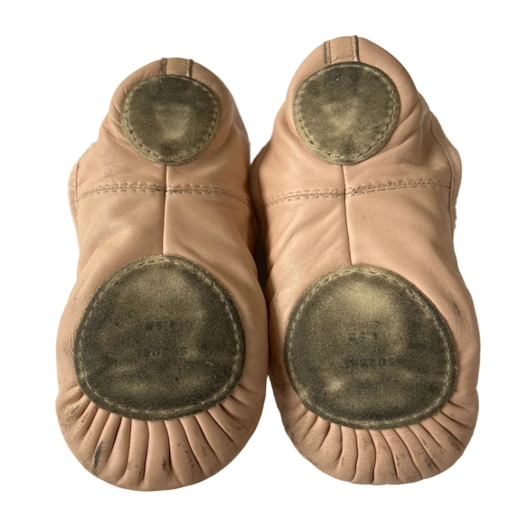 A pair of leather ballet shoes shown from the sole, displaying the circular cork footbeds and stitched seams on a plain white background.
