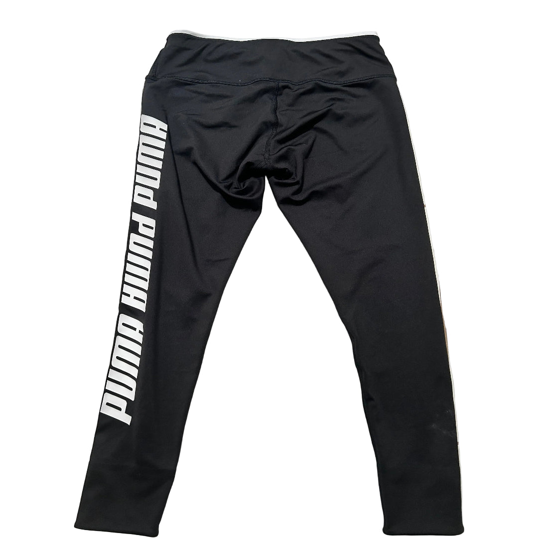 Black athletic leggings with a bold white vertical 'PUMA PUMA PUMA' text print on the left leg, laid flat on a white background