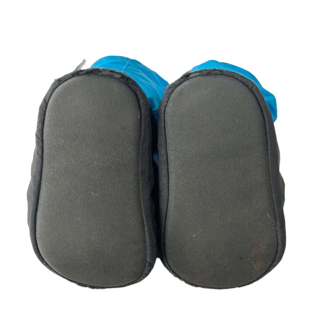 A pair of black slip-on slippers or boot covers shown from the sole side, with bright blue fabric lining or cuffs visible at the top, photographed on a plain white background.
