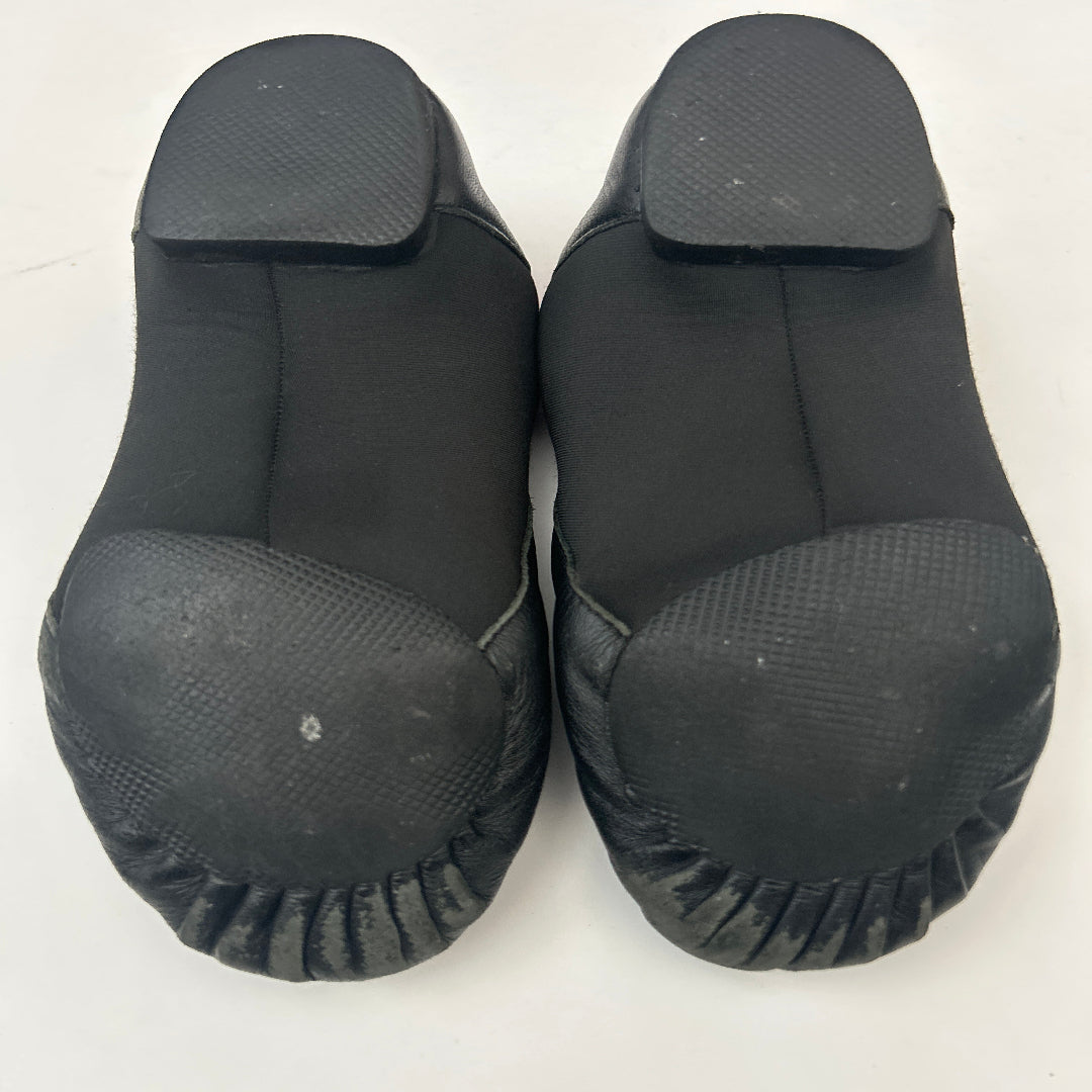 A pair of black dance shoes with textured rubber toes and flexible black fabric uppers, photographed from above on a plain white background.