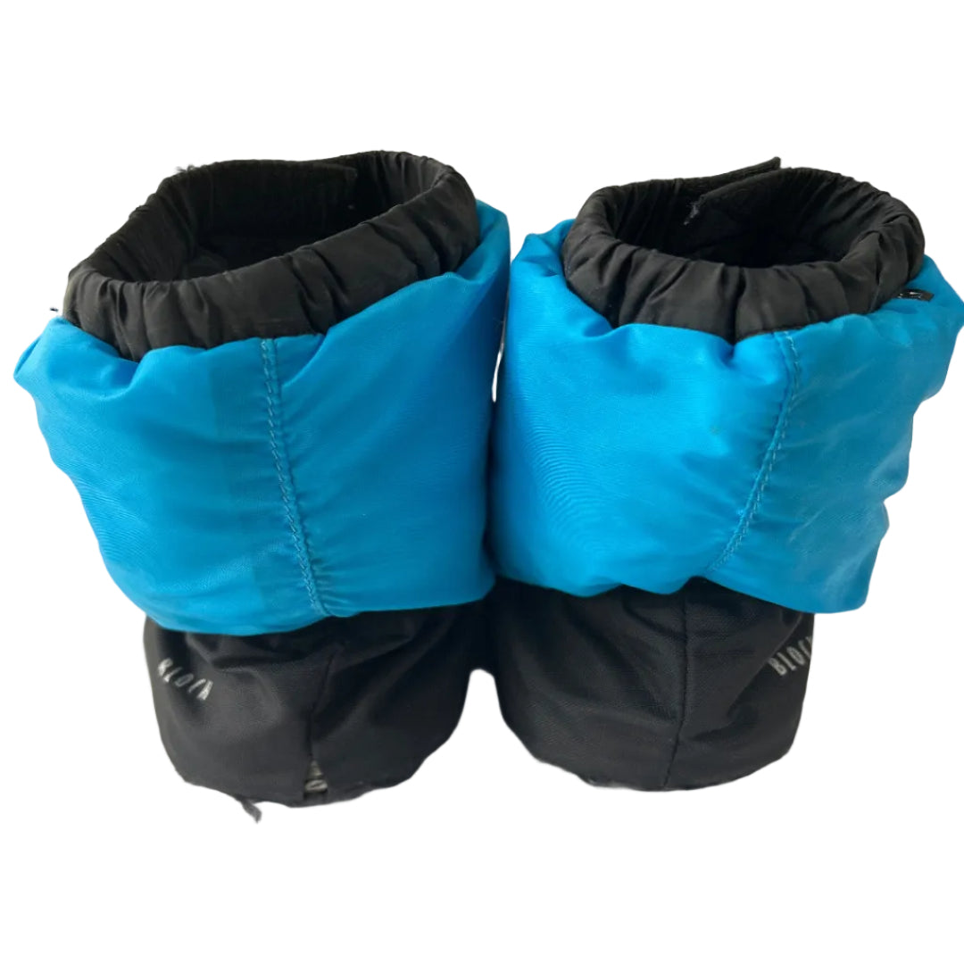 A pair of bright blue and black boot covers or gaiter sleeves shown from the back, photographed on a plain indoor surface.