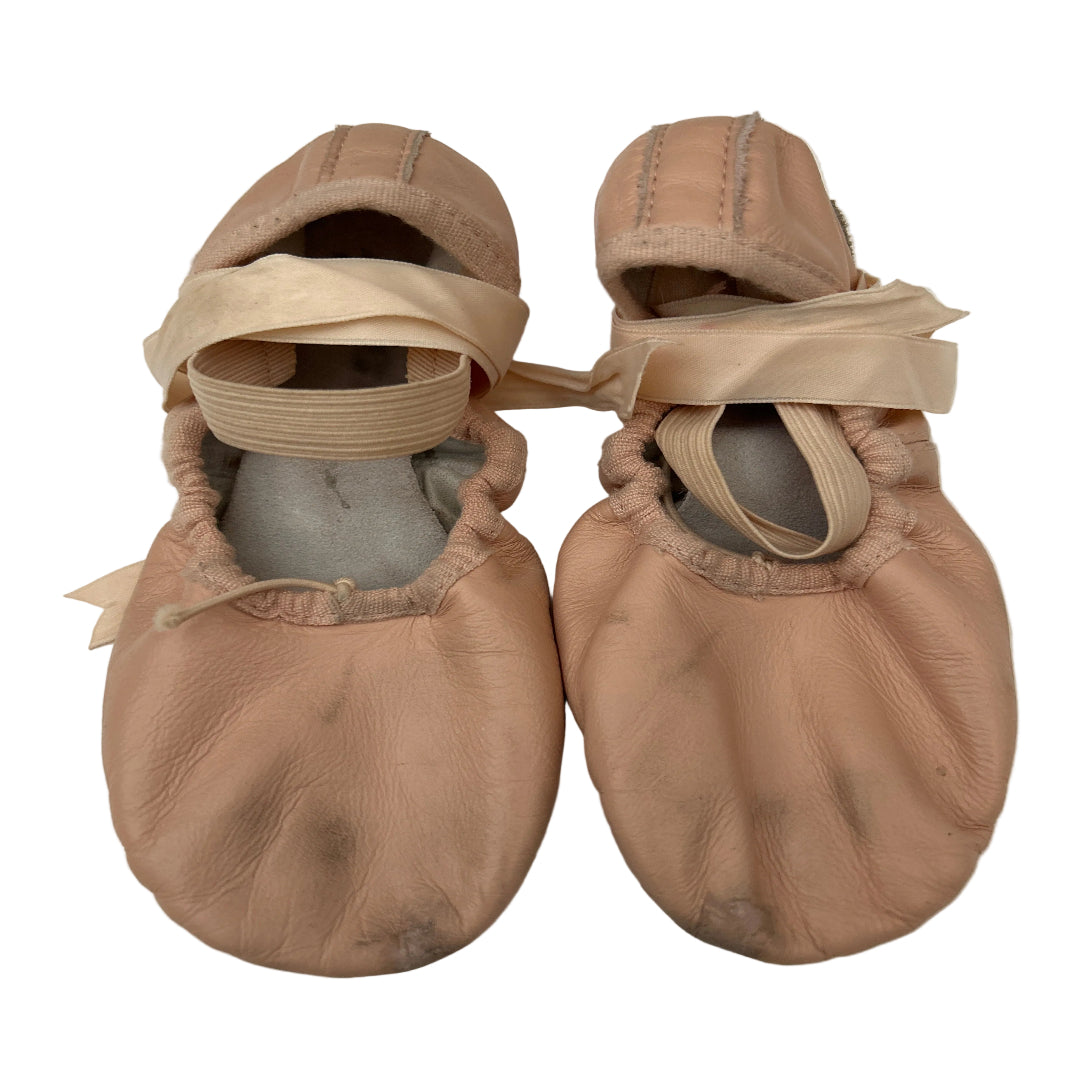 A pair of leather ballet shoes with matching satin ribbon ties, laid flat on a white background.